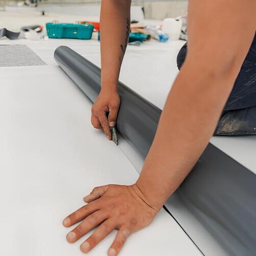 worker laying down TPO roofing