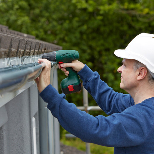 Workman Replacing Guttering On Exterior Of House