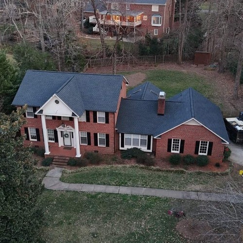 a front view of a brick home with a shingle roof