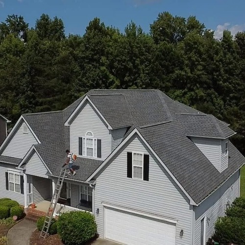 a worker inspecting a shingle roof